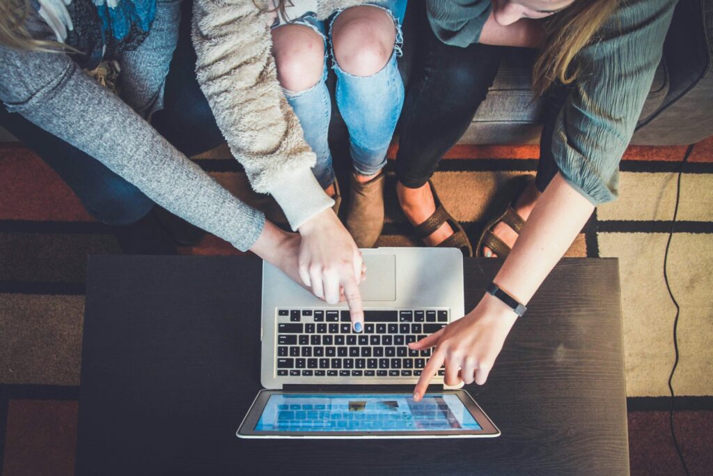 Three people gathered around a laptop, pointing at the screen
